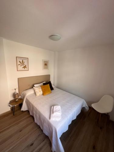 a bedroom with a bed and a white chair at AB Apartamentos in Melilla