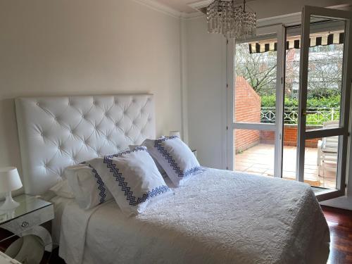 a white bedroom with a bed with pillows on it at Apartamento con Jardín in Getxo