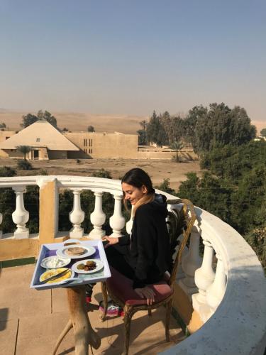 a woman sitting at a table with a plate of food at Sakkara pyramid inn hotel in Cairo