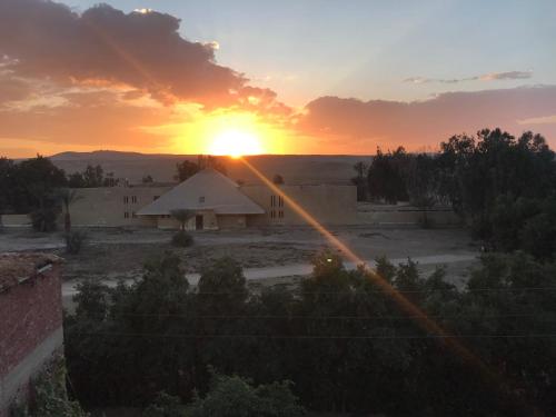 a sunset over a building with the sun in the sky at Sakkara pyramid inn hotel in Cairo