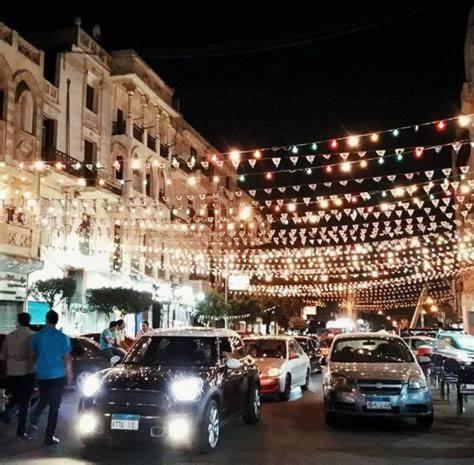 eine Gruppe von Autos, die auf einer Stadtstraße mit Lichtern geparkt sind in der Unterkunft VIP 2BHK Presidential neighborhood KOURBA- BGhomes in Kairo