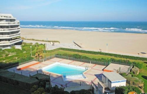 - une piscine à côté d'une plage et d'un bâtiment dans l'établissement LE JARDIN DE LA PLAGE - T2 - Terrasse jardin 30m2 - Piscine - Clim- Wifi -Parking, à Canet