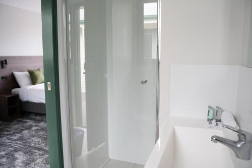 a bathroom with a shower and a sink and a tub at Wallaby Hotel in Gold Coast