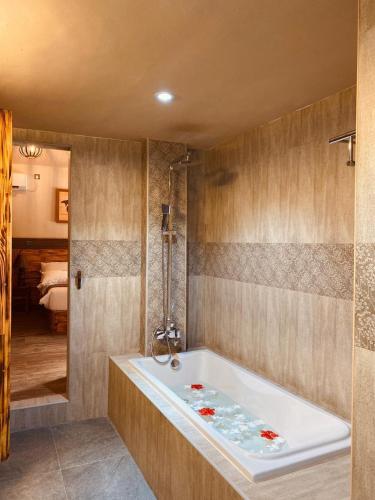 a bathroom with a bath tub and a bedroom at Sand Inn Residence in Kamadhoo