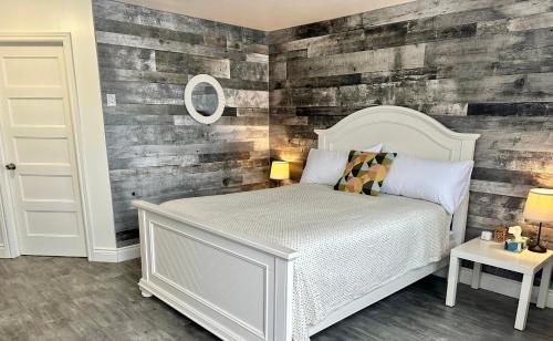 a bedroom with a white bed and a wooden wall at Cheticamp Outback Inn in Chéticamp