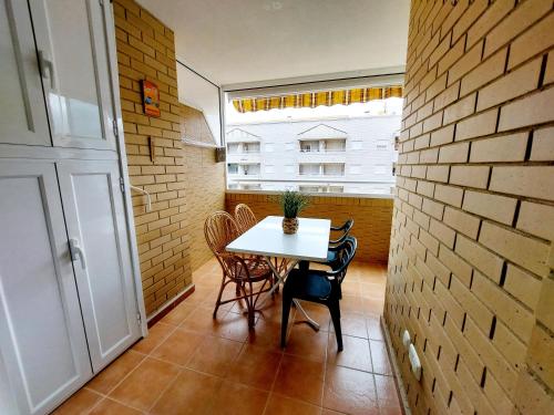 a table and chairs in a room with a brick wall at Apartamento Neptuno Sunrise Magic World in Oropesa del Mar