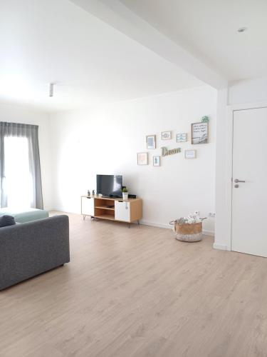 a white living room with a couch and a tv at Ericeira Vibes in Ericeira
