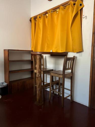 南聖胡安的住宿－Buena Onda Backpackers，一张带黄色窗帘的桌子和两把椅子