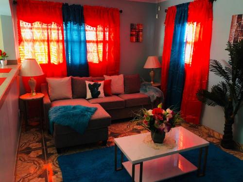 a living room with red and blue curtains and a couch at JB's Cottage in Bottle Creek Settlements