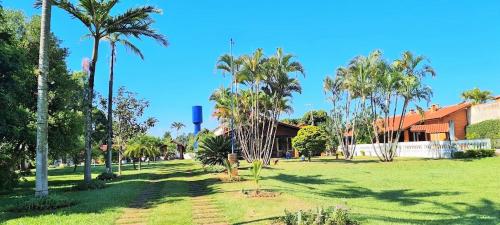 a park with palm trees in front of a building at Chácara em Boituva com piscina e churrasqueira in Boituva