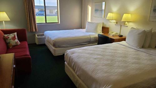 Habitación de hotel con 2 camas y sofá rojo en Carlyle Inn & Suites, en Carlyle