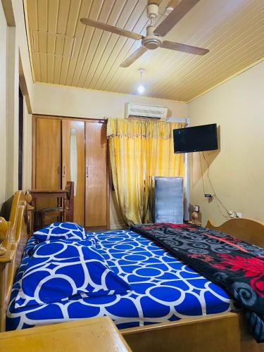 a bedroom with a bed and a ceiling fan at Tuxedo Hotel in Accra