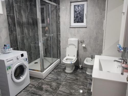 ein Bad mit einer Dusche, einem WC und einer Waschmaschine in der Unterkunft Apartman TT Stan na dan Trn Laktaši in Laktaši