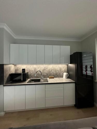 a kitchen with white cabinets and a black refrigerator at Apartament Różana in Lublin