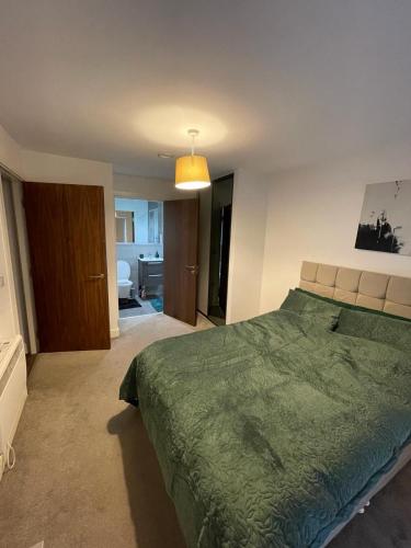 a bedroom with a green bed and a bathroom at Room in Modern Luxury 3 bed Apartment in City Center in Birmingham
