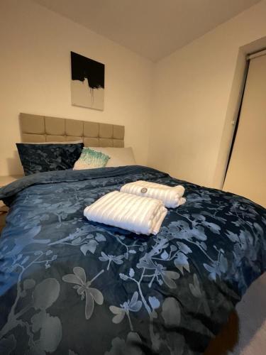 a bed with two white towels on top of it at Room in Modern Luxury 3 bed Apartment in City Center in Birmingham