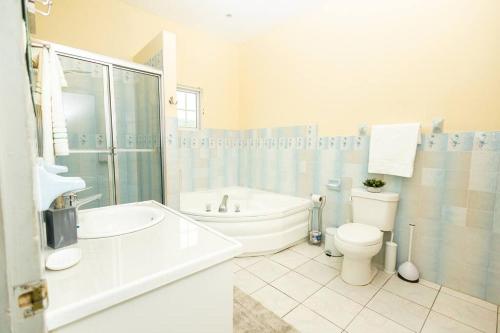 La salle de bains est pourvue d'une baignoire, de toilettes et d'un lavabo. dans l'établissement Sun Haven Villa in Discovery Bay, St. Ann, à Discovery Bay