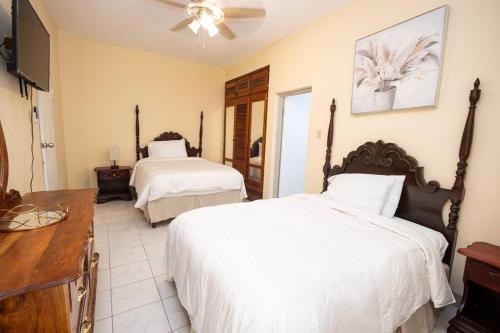 Cette chambre comprend deux lits et une télévision. dans l'établissement Sun Haven Villa in Discovery Bay, St. Ann, à Discovery Bay