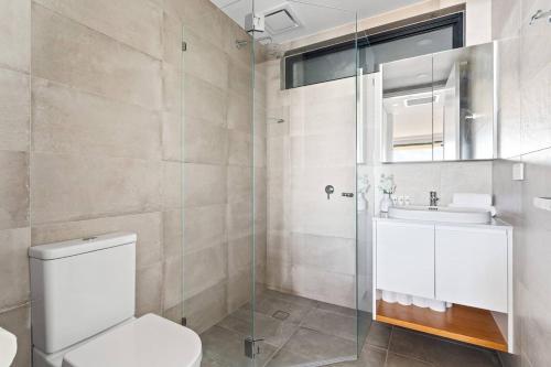 a bathroom with a toilet and a sink and a shower at Ocean Views, Deck and Parking at Beach Apartment in Collaroy