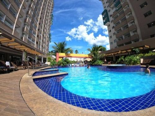 a large swimming pool in a resort with blue water at Flat encantador com piscinas aquecidas, academia e playground in Olímpia