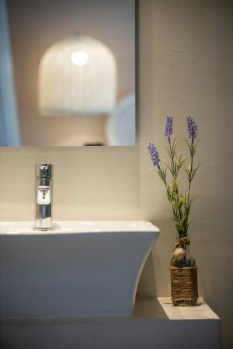 a bathroom sink with a vase with purple flowers in it at Mari Kristin Beach Hotel in Hersonissos
