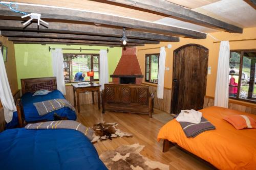 ein Wohnzimmer mit 2 Betten und einem Kamin in der Unterkunft Refugio de Montaña Huerta Sacha in Chaupi