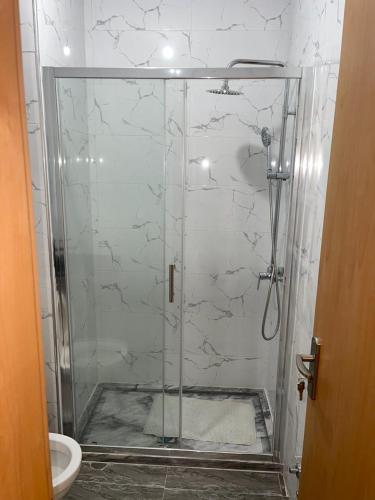 La salle de bains est pourvue d'une douche avec une porte en verre. dans l'établissement madison place, à Praia