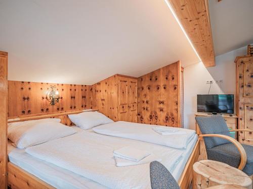 a bedroom with a bed and two chairs and a television at Röck XL in Neukirchen am Großvenediger