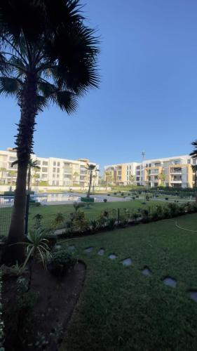 a palm tree in a park with buildings in the background at Appartement Prestigia des nations in Salé