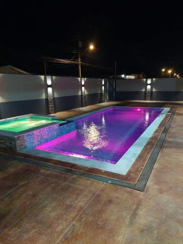 uma piscina à noite com luzes roxas em Eastland Villa em Sangre Grande