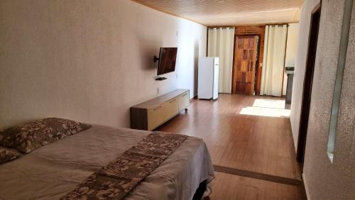 a bedroom with a bed and a white refrigerator at Penedo Chalés Bela Vista 10 in Itatiaia
