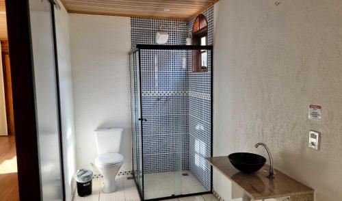 a bathroom with a toilet and a glass shower at Penedo Chalés Bela Vista 10 in Itatiaia