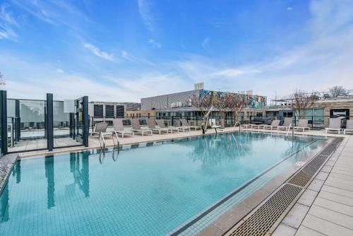 a large swimming pool with chairs and a building at 2BR Furnished Apartment Near Nationals Park in Washington, D.C.