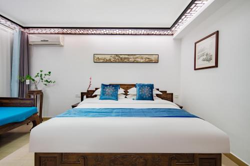 a bedroom with a large bed with blue pillows at Tongli Lanshe Garden B&B in Suzhou
