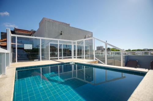 a swimming pool on the roof of a house at Zuza Slim Suítes in Maceió