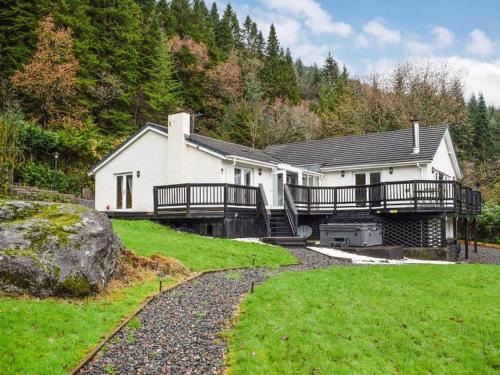 a large white house with a porch and a deck at WATERSIDE 3 BED COTTAGE, HOT TUB, SAUNA, PVT BEACH in Arrochar