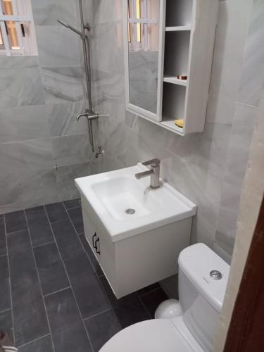 a bathroom with a white sink and a toilet at Appartement à Fidjrossè in Cotonou