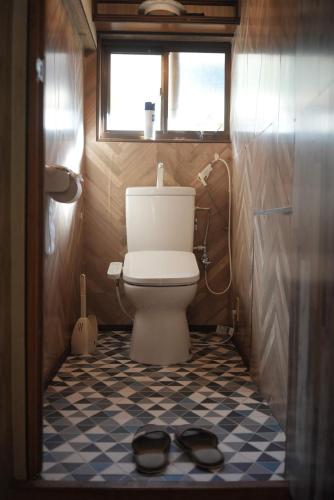 a bathroom with a toilet and a pair of shoes on the floor at omusubi guest house (JAPANESE　STYLE） in Mamihara