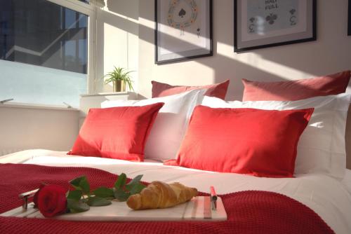 uma cama com almofadas vermelhas e uma bandeja de croissants em 10 min to Buckingham Palace-Central 1BR Flat-Sleeps 5 em Londres