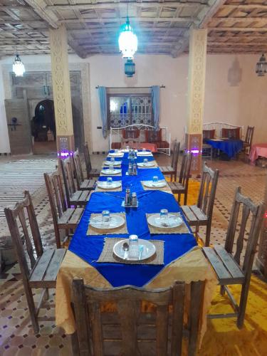 een lange tafel in een kamer met blauwe tafelkleden bij SANDSTAR PALACE in Merzouga