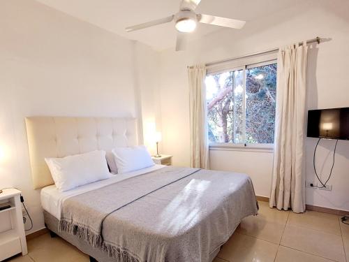 a white bedroom with a bed and a window at Rivadavia 644 in Pinamar