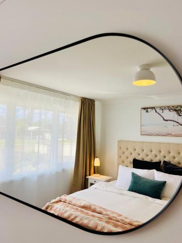 a mirror reflecting a bed in a bedroom at Sunshine Retreat Modern 3BR Haven in St Marys