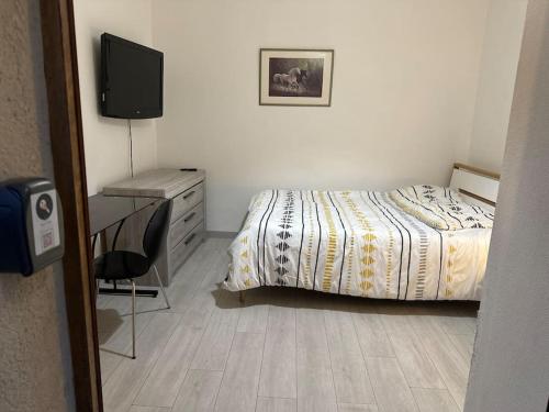 une chambre avec un lit, un bureau et une télévision dans l'établissement Oasis, à Besançon