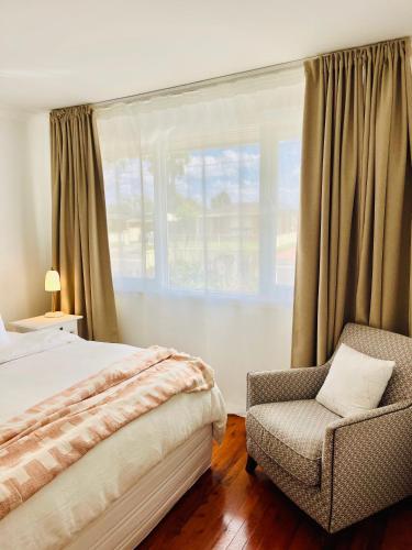 um quarto com uma cama, uma cadeira e uma janela em Sunshine Retreat Modern 3BR Haven em St Marys
