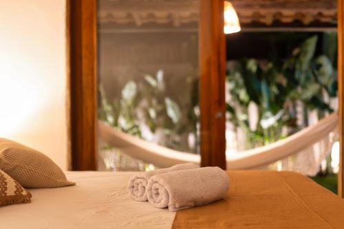 een handdoek op een bed voor een spiegel bij Casa Vivá in Arraial d'Ajuda