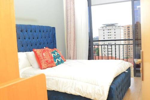 a bed with a blue headboard in a room with a window at Spacious, beautiful, elegant, with natural light 1 bedroom Apartment in Nairobi
