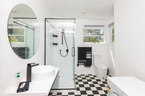 a bathroom with a shower and a sink and a mirror at Art Deco Charm - Amazing River Views Inner City in Gisborne