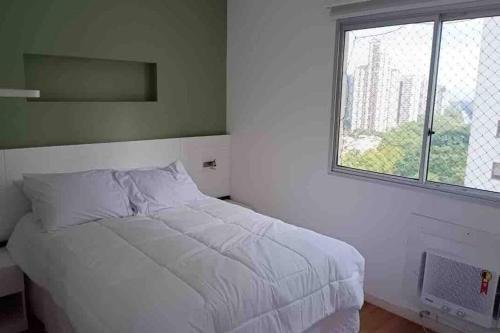 a white bed in a bedroom with a window at Ap na Barra da Tijuca, atrás do Windsor in Rio de Janeiro