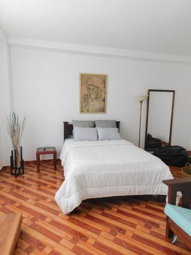 a bedroom with a white bed and a wooden floor at Hostal Santa Teresita in La Merced