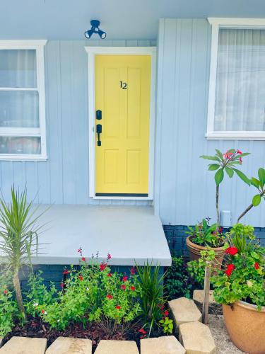 a yellow door on the front of a house with flowers at Sunshine Retreat Modern 3BR Haven in St Marys